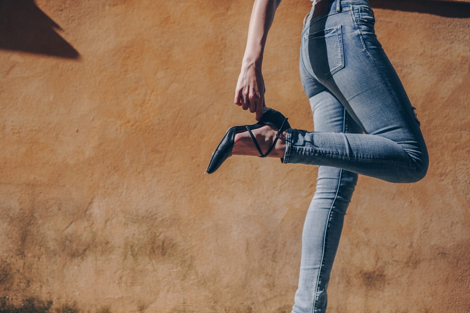 Woman changing Mestrae heel against terracotta wall